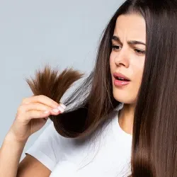 Woman holding her hair and staring at it 