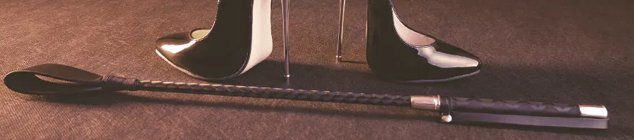 A bondage whip and black high heels on the floor